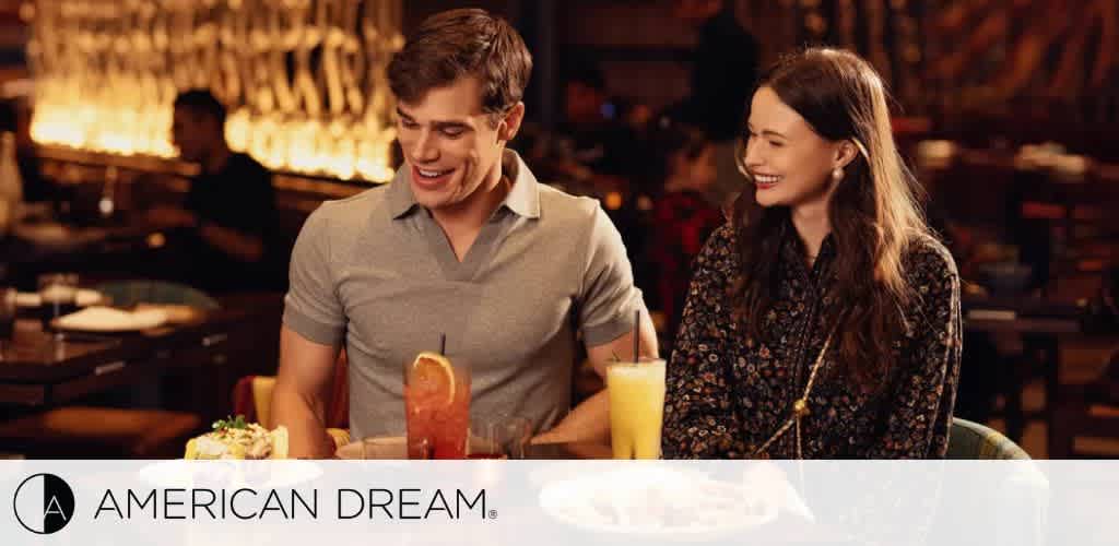 A smiling man and woman sitting at a restaurant table with drinks.