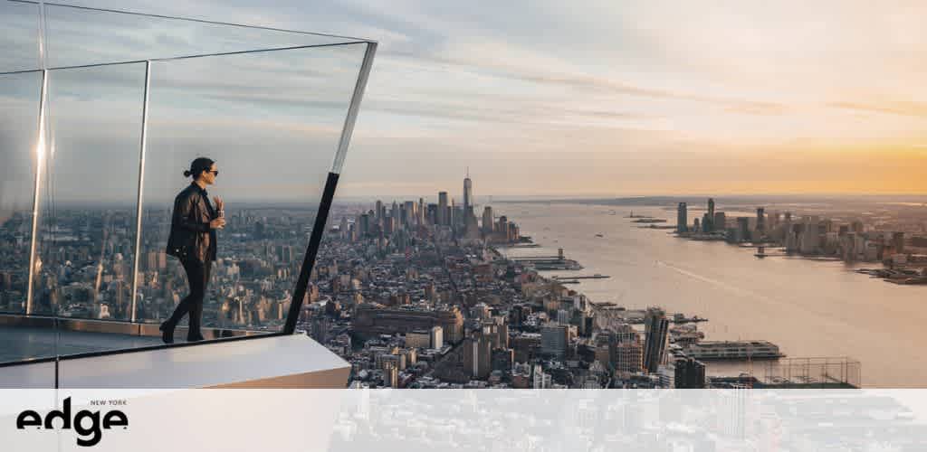 Image shows a person observing city views from a glass observation deck at sunset. The sweeping urban panorama highlights dense skyscrapers and busy waterways. The deck logo is visible.