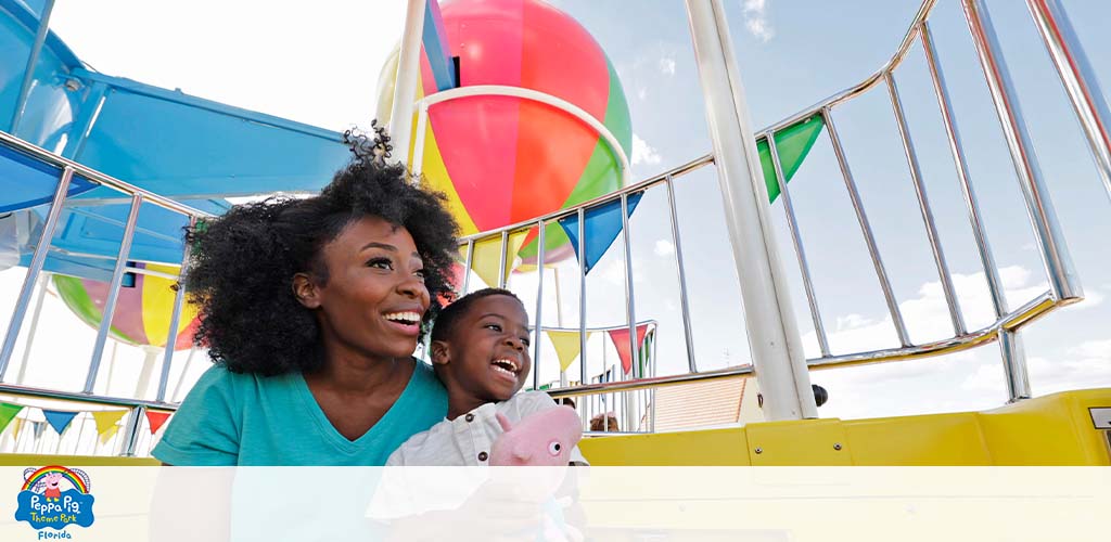 A joyful woman and child riding a colorful ferris wheel under a blue sky.