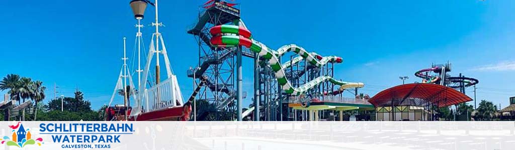 Image shows Schlitterbahn Waterpark in Galveston, Texas. A clear blue sky serves as a backdrop for multiple colorful water slides and attractions, including a ship-themed structure. Palm trees add to the sunny atmosphere.