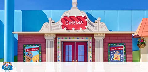 A colorful animated cinema facade with posters and a clear sky.