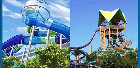 Two water slides in an amusement park with blue skies and greenery.