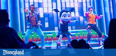 Performers on stage at a Disneyland show with animated character.