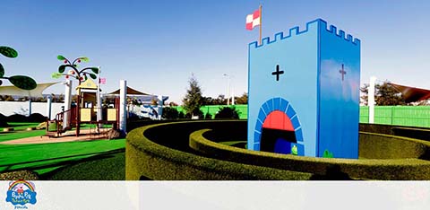 A colorful castle and hedge maze in a children's playground area.