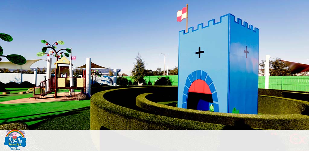 A colorful playground with a hedge maze and a blue castle-like structure.