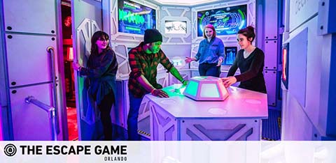 Four people at a colorful, futuristic escape game room in Orlando, interacting with a puzzle.