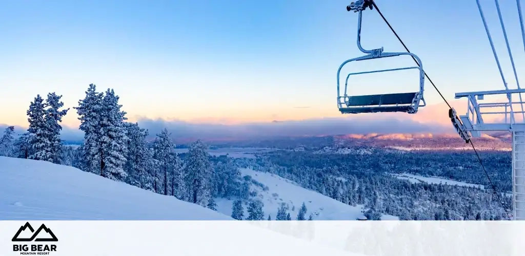 Image description: This panoramic image captures the serene beauty of a snowy landscape at Big Bear Mountain Resort. The sky transitions from a pale blue to soft hues of pink and orange as the sun sets in the distance. A ski lift with empty chairs hangs above the well-groomed slopes, providing a clear view of the distant horizon where the sky meets the treeline. Snow-dusted pine trees add a touch of tranquility to the wintery scene. The left side of the photo shows a slope leading down to the forest, while to the right the ski lift structure stands out against the sky. The Big Bear Mountain Resort logo is prominently displayed in the lower left corner.

Remember, at GreatWorkPerks.com, we're committed to bringing you the lowest prices and significant savings on your tickets for incredible experiences like this one at Big Bear Mountain Resort!