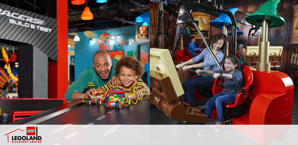 Image of a vibrant indoor play area at LEGOLAND Discovery Center. A man and a child smilingly display a LEGO car creation at a Racer's Build & Test station. In the background, a woman and girl enjoy a simulated ride attraction, with realistic controls and movement, surrounded by colorful decor and playful lighting.