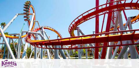 Image shows a brightly painted red and yellow roller coaster with intricate loops and curves under a clear blue sky. The coaster is part of Knott's Berry Farm amusement park. There are no visible riders on the track.