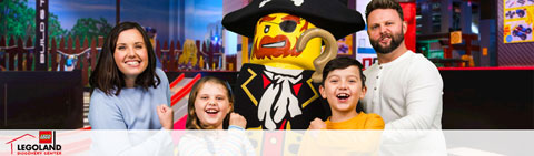 This image features a smiling family of four at a LEGOLAND Discovery Center, standing next to a life-sized LEGO pirate character. From left to right, there's a woman with shoulder-length brown hair wearing a blue top, a young girl with blonde hair in a yellow sweater grinning widely, a young boy with brown hair wearing an orange shirt, also smiling, and a man with facial hair and brown hair in a black shirt. In the background, colorful LEGO structures can be seen, adding to the playful atmosphere of the scene.

At FunEx.com, we take pride in offering our customers the opportunity for memorable experiences at the lowest prices - don’t miss out on our exclusive discounts and save on tickets to your favorite family attractions!