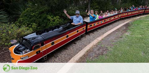 Image shows a miniature train with passengers at San Diego Zoo. A person at the front is waving, while others enjoy the ride amidst green foliage. The logo of San Diego Zoo is visible in the corner.