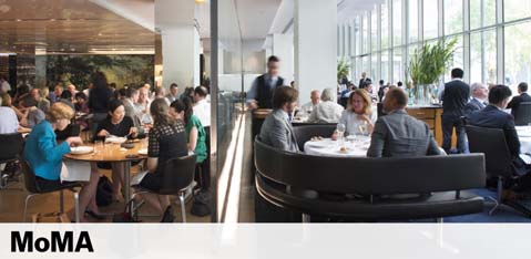 Image shows a bustling café setting inside the MoMA with patrons seated at tables. Some engage in conversation while others enjoy their meals. Large windows offer a view of greenery outside, contributing to the café's bright and airy atmosphere. The MoMA logo is visible at the bottom.