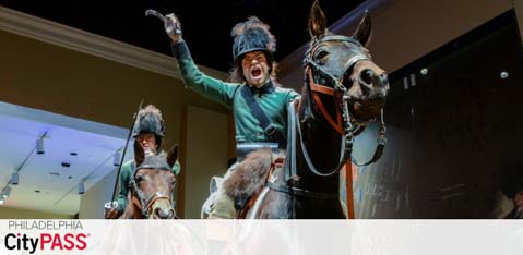 Promotional image for Philadelphia CityPASS featuring two life-sized models of soldiers riding horses. The forefront figure is gesturing triumphantly. They're wearing historic military attire, suggesting an exhibit or attraction related to Philadelphia's rich history. The CityPASS logo is in the corner.