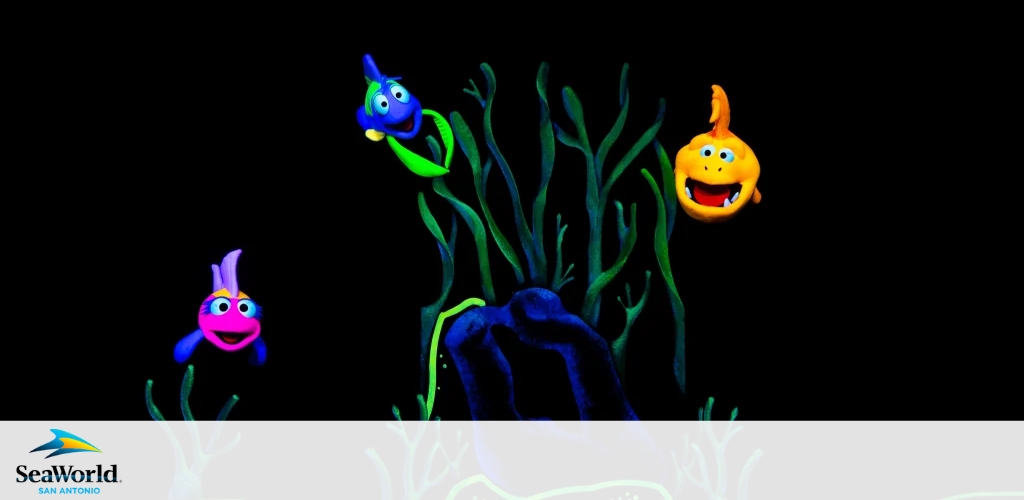 Image depicts three brightly colored, stylized animated sea creatures amidst seaweed against a dark background. SeaWorld San Antonio logo visible.