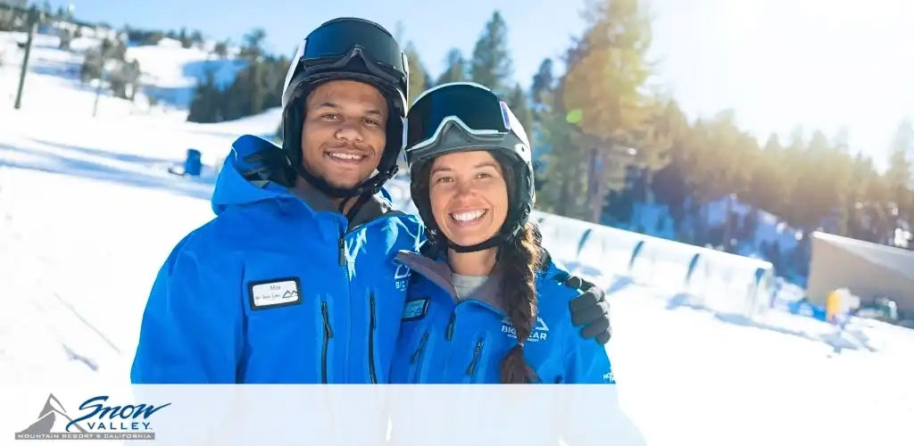 This image features a joyful man and woman standing close together on a sunny winter day at a ski resort. Both individuals are wearing vibrant blue jackets with a logo that reads "BIG BEAR" and a mountain graphic, indicating they may be staff or instructors at the resort. The jackets also have name badges, although the names are not legible. They are equipped with black helmets and are smiling broadly at the camera. The backdrop reveals a snowy landscape with mountains and a clear blue sky. The resort's logo, "Snow Valley Mountain Resort California," is visible in the bottom right corner of the photograph.

As you plan your upcoming snowy adventure, don't forget to check out GreatWorkPerks.com for exclusive discounts on tickets, ensuring you find the lowest prices for your mountain getaway.