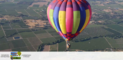 Image Description: A vibrant hot air balloon adorned with bold vertical stripes in a spectrum of colors - red, orange, yellow, green, blue, and purple - is seen aloft. Below the balloon, a patchwork of farmland extends into the distance, suggesting a calm, clear day favorable for flying. The greenery of the fields is intersected by the geometric lines of the plots, adding to the idyllic rural tableau. There are logos and text at the bottom edge of the image which appear to be promotional or informational, but their specific content isn't described.

End your next adventure on a high note and soar above the rest with GreatWorkPerks.com—your destination for the highest savings and the lowest prices on event tickets and thrilling experiences.