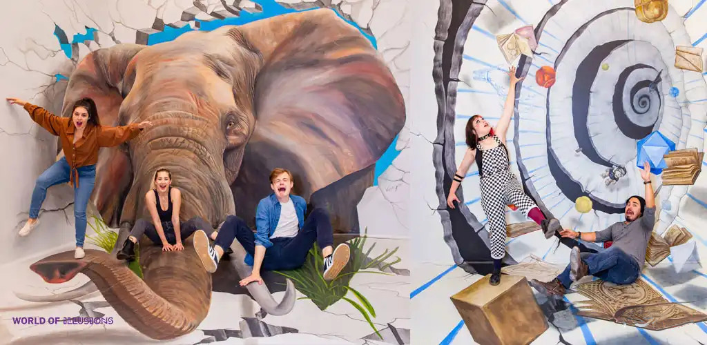 This image showcases two different interactive three-dimensional art installations at the World of Illusions. On the left, there is a large, lifelike painting of an elephant’s head and trunk breaking through a cracked blue and white wall. Above the elephant, three individuals are positioned playfully as if they are sliding down the trunk; two women and a man, who appear to be enjoying themselves, are dressed in casual clothing. On the right side, there is an illusion designed to make it look like a vortex tunnel with floating geometric shapes and clocks. Two people are pictured; a woman in a checkered outfit stretched out as if caught in mid-fall, reaching for floating books, and a man seated on a sideways block, also pretending to be in a state of suspension. They both look surprised and are engaging with the artwork in a way that enhances the illusion.

Shopping for experiences at GreatWorkPerks.com offers not only unforgettable memories but also unbeatable savings – ensure to snag your tickets at the lowest prices available!