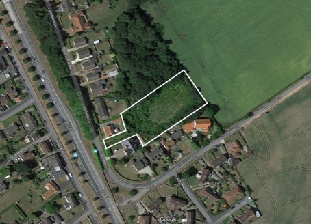 The site is set back from Lunnsfield Lane, and is accessed between numbers 25 and 27, and with the exception of the access it comprises a mainly rectangular plot with is bordered by fields or the gardens of neighbouring properties.