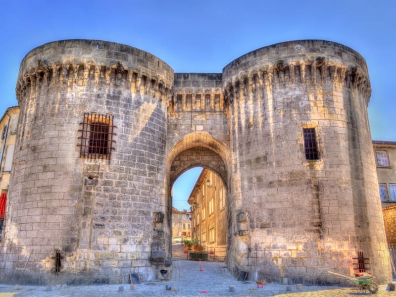Massive round stone towers forming a medieval gate into the old town of Cognac