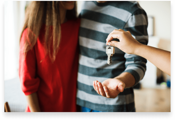 Young couple getting keys to their first real estate investment property