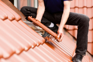 Dachdecker deckt Dach mit Dachziegel ein.