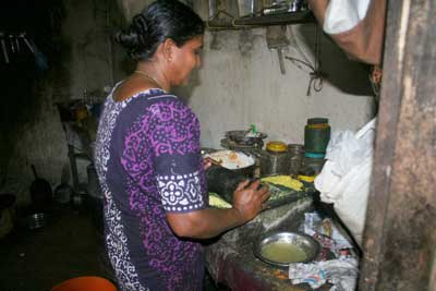 Working in Kerala kitchen grinding coconut on a stone.