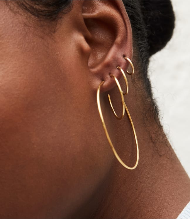 women ear wearing different sizes of 4 gold hoop earrings