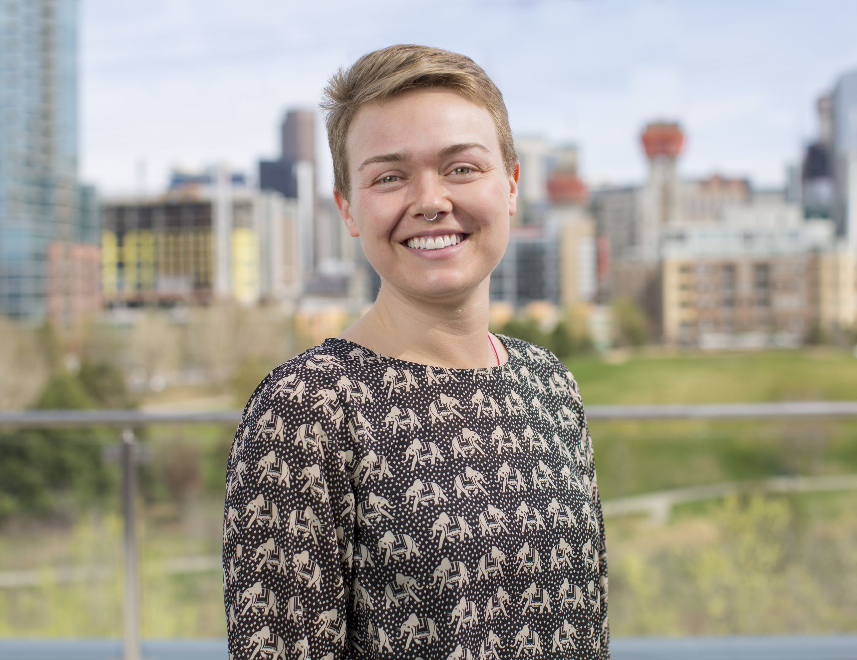 A headshot of Kim Schlesinger on the patio of the Galvanize Platte Location. She is wearing a black shirt with an elephant pattern and is smiling at the camera