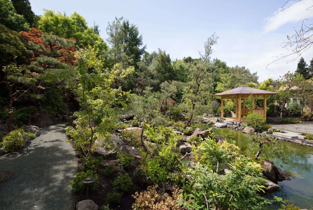 view of path, trees, pond, and gazebo