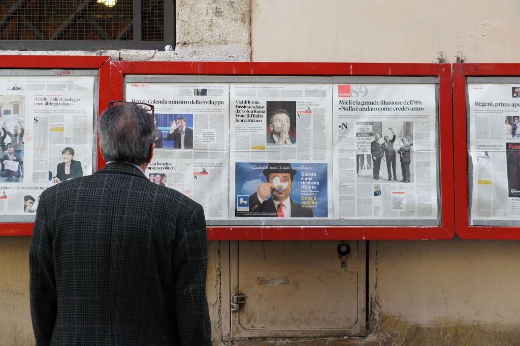 Photo of a man looking at newspapers on display