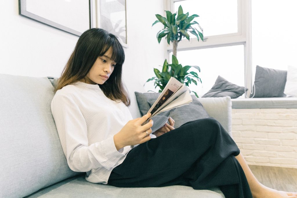 Photo of a woman sitting on a sofa reading a newspaper