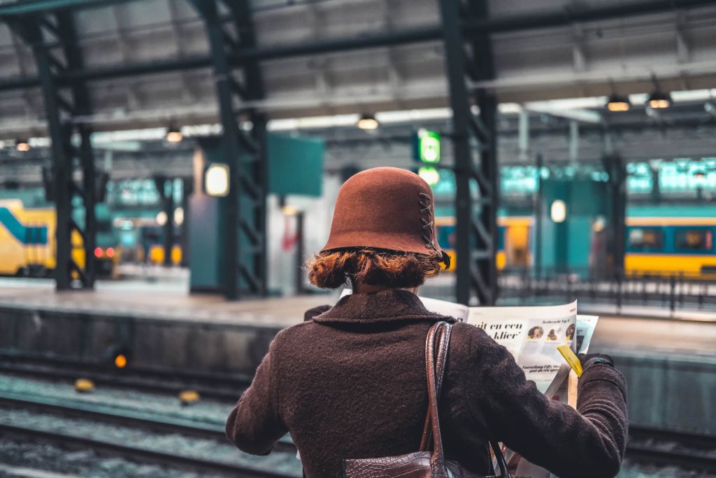 Image of a woman holding a newspaper standing on a train platform