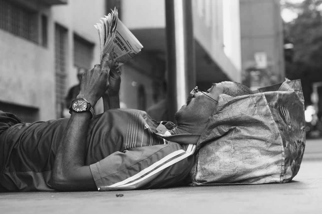 Man laying down reading a newspaper