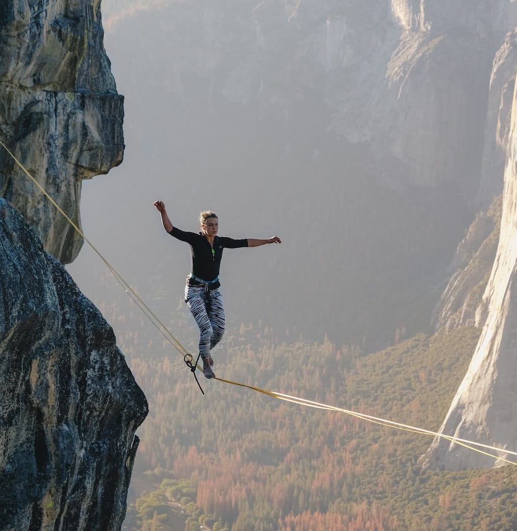 photo of a woman walking a tightrope over a cliff as a metaphor for the precarious nature of startups