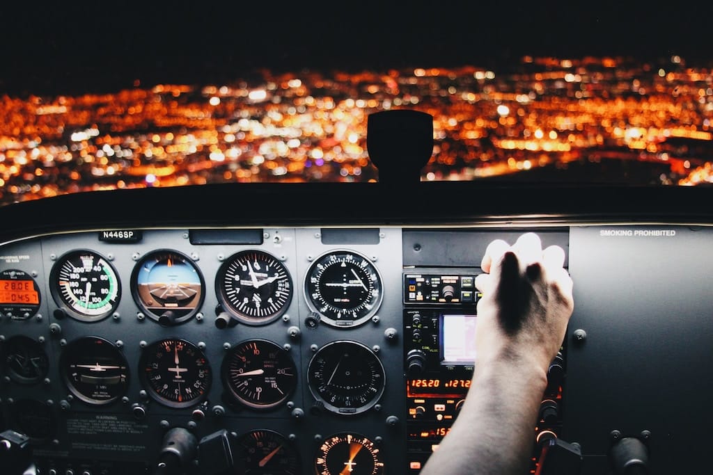 Photo of a pilot at the controls of an airplane flying at night