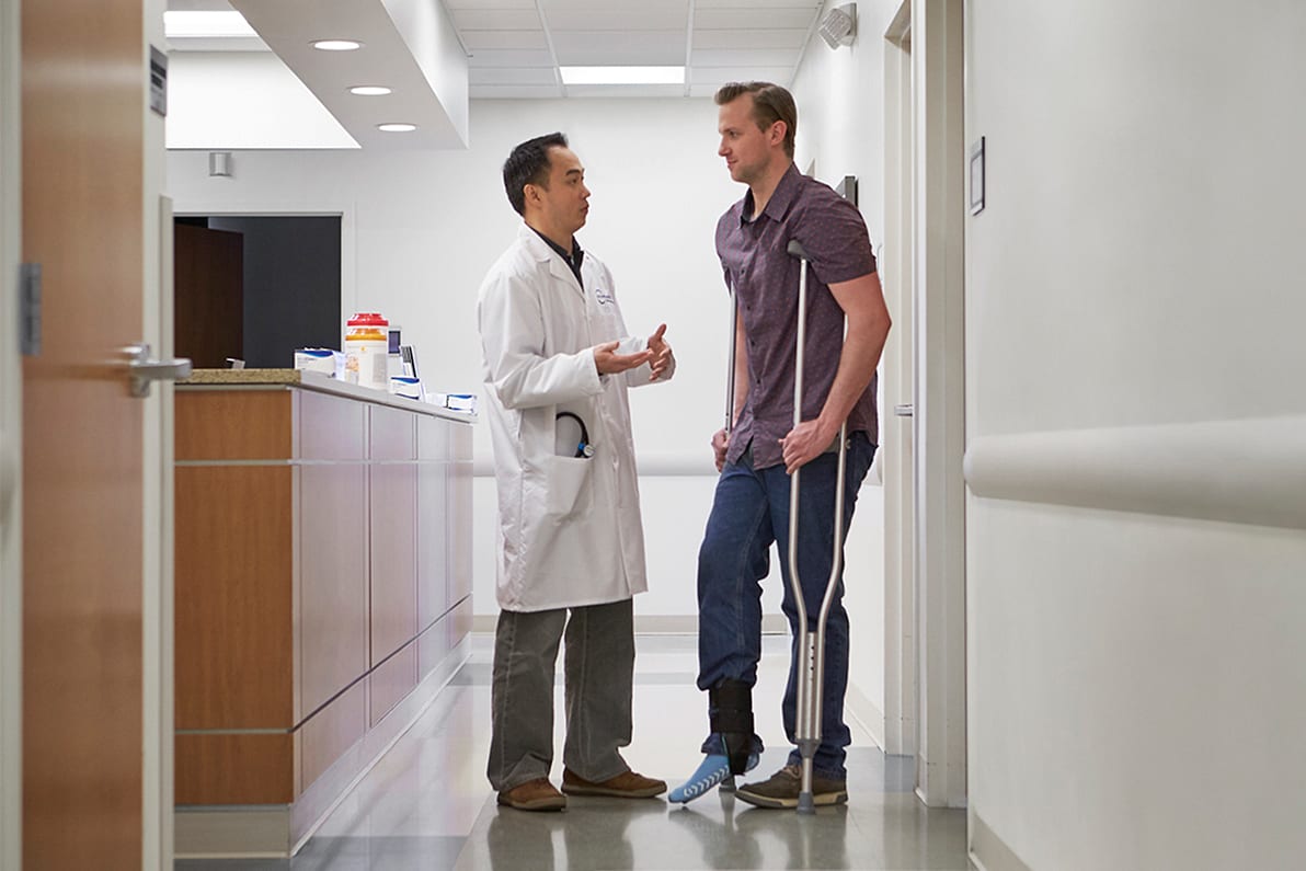 Doctor speaking to man on crutches