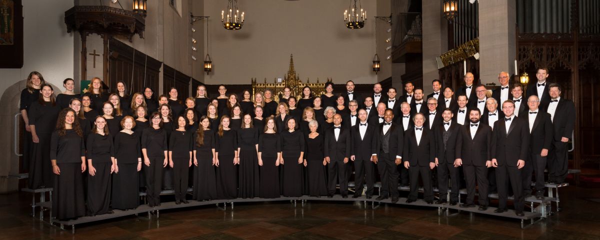 Singers standing on risers in black and white concert dress. 