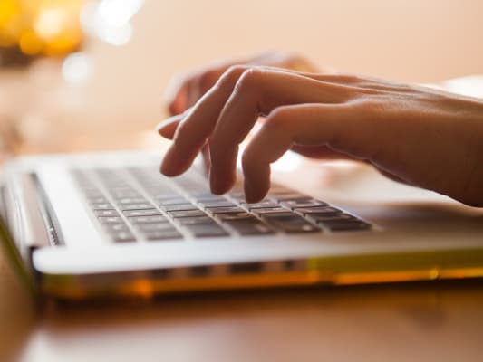 Hands typing on laptop