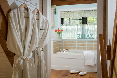 jacuzzi tub with 2 robes hanging on wall