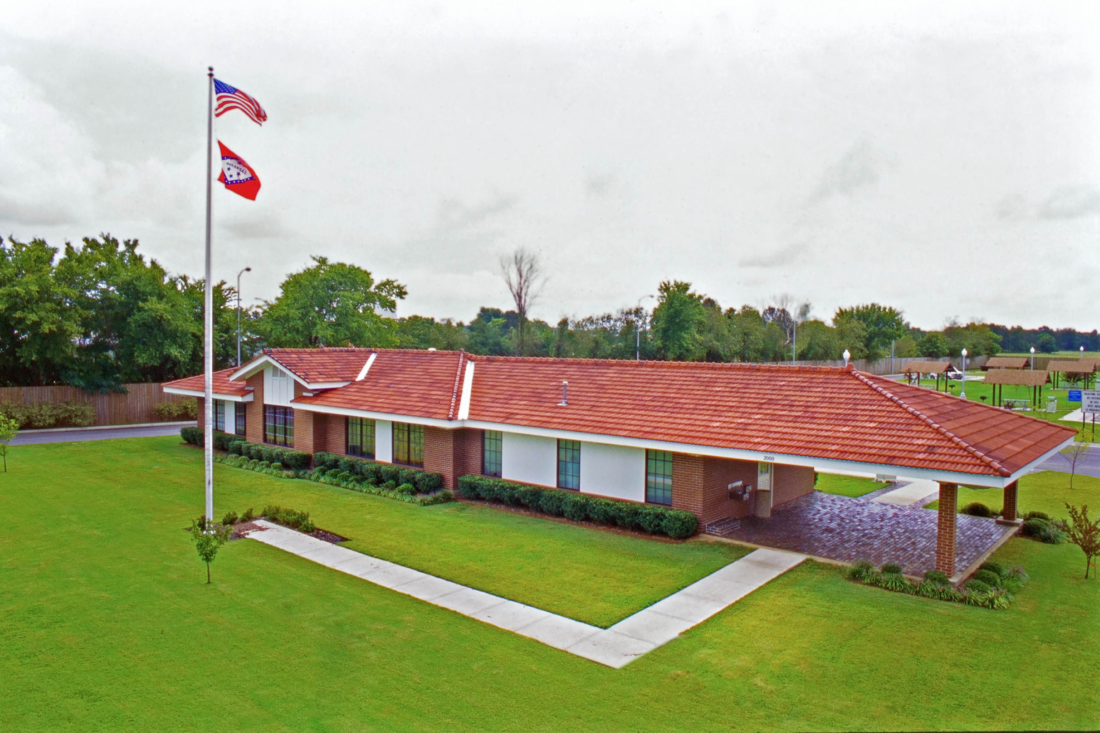 Exterior, arial view of a long, one story building with a red shingle roof.