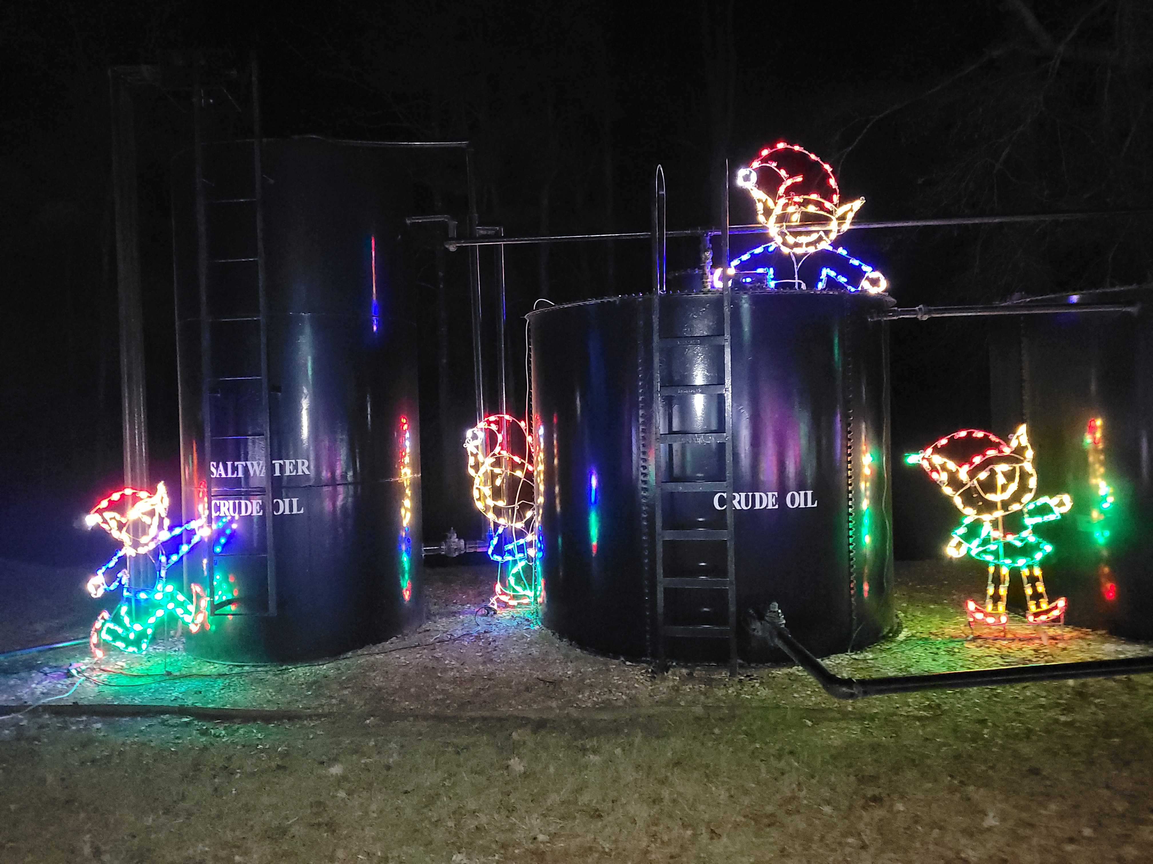 Lighted elf displays atop oil storage tanks
