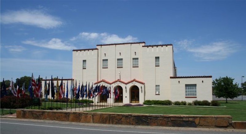 A white building with flags lining the path to the entrance.