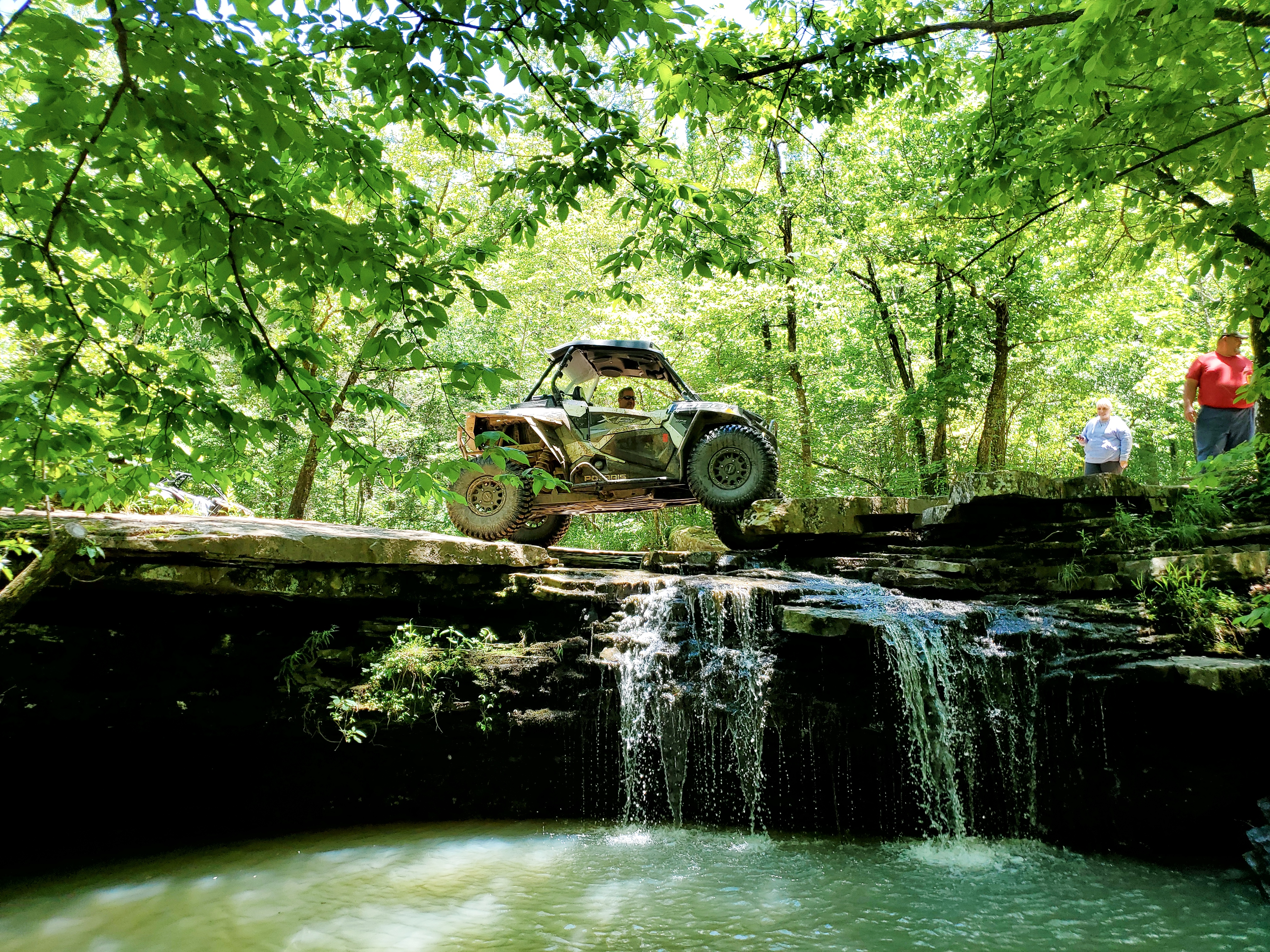 Side-by-side vehicle on top of a waterfall in the forest. 