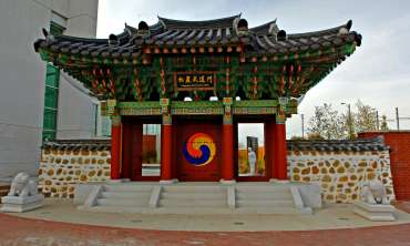 Strikingly large gate built in the South Korean Hongsalmun style, painted with bright colors and decorated with symbols. 