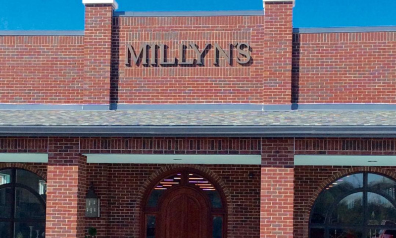 Stately brick storefront with large arched double doorway and gold signage reading Millyn's.