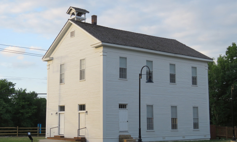 White, two-story building with bell tower on roof.