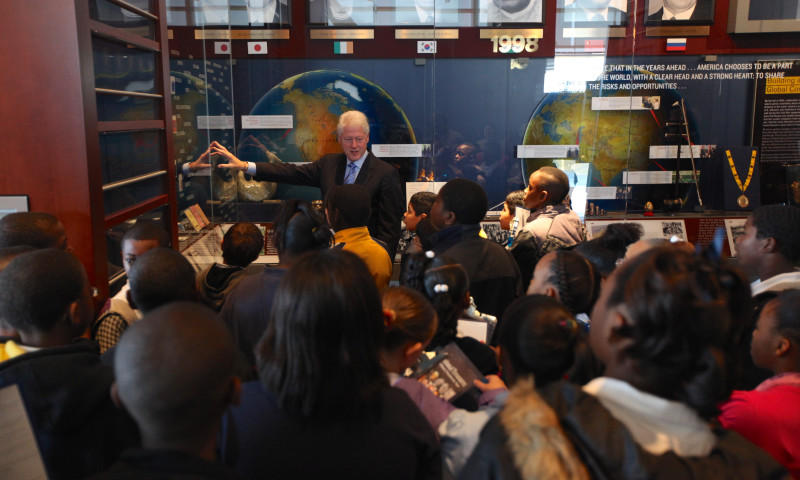 President Bill Clinton speaks with a group of students inside the Clinton Presidential Center's permanent exhibits
