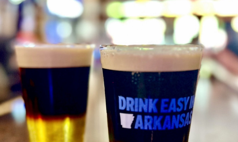 Two pint glasses filled with black and tan sitting on the bar. 