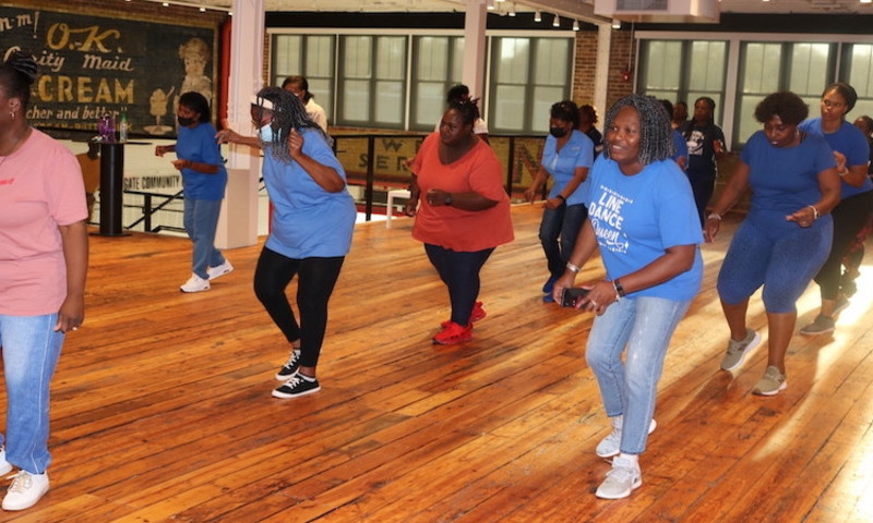 A group of women take a dance class in a large studio space at The Arts & Science Center.