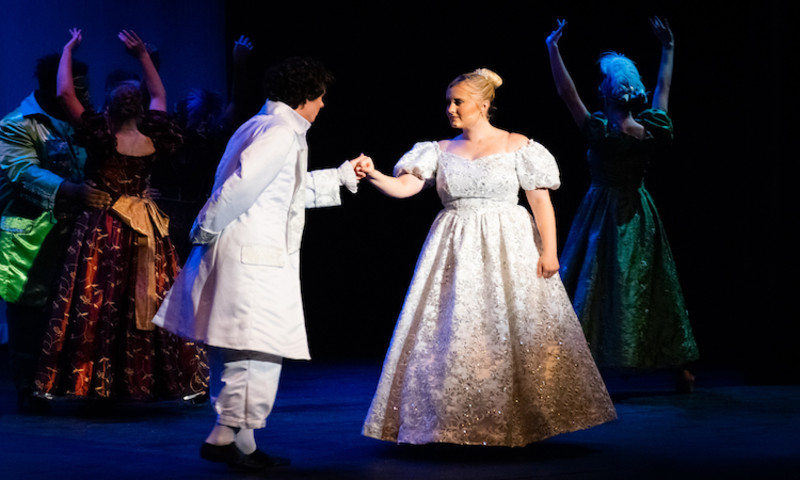 Performers stand on stage in elaborate costumes acting out “Rodgers & Hammerstein’s Cinderella.”